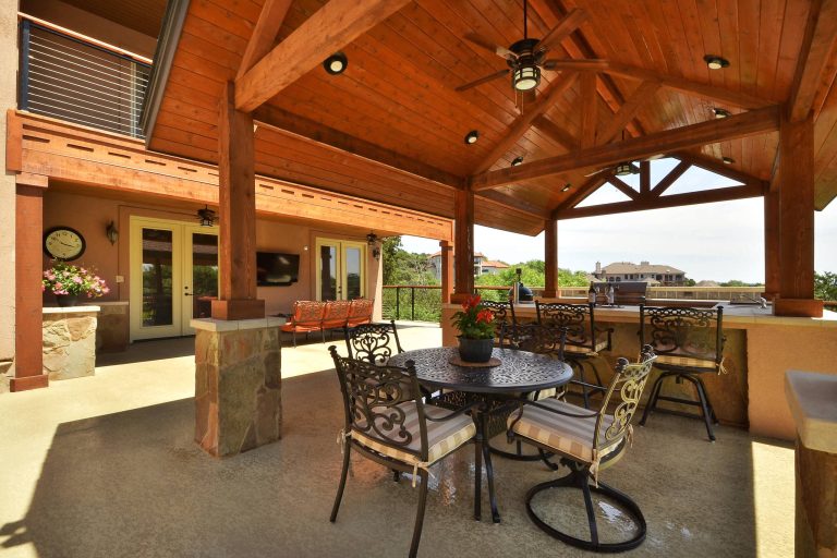 Custom outdoor kitchen, sitting area, and solid roof cabana by Southern Landscape. The entire project was constructed by leveling a severe slope with a concrete block retaining wall.