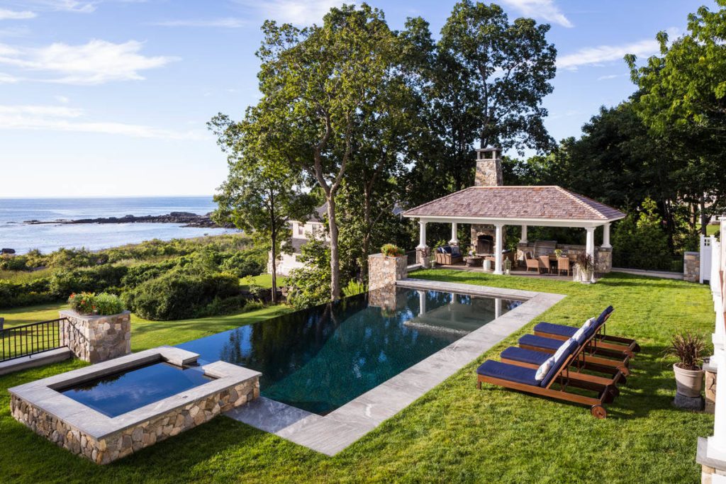 Custom stone outdoor pool patio, hot tub, outdoor kitchen, staircase, walkways, patio and gardens. High end outdoor living on the southern coast of Maine.