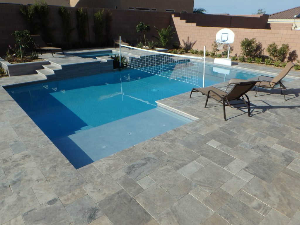 Custom swimming pool and spa with built in table and benches, umbrella sleeves, volleyball net sleeves, water basketball net, spillover raised spa, integrated planters