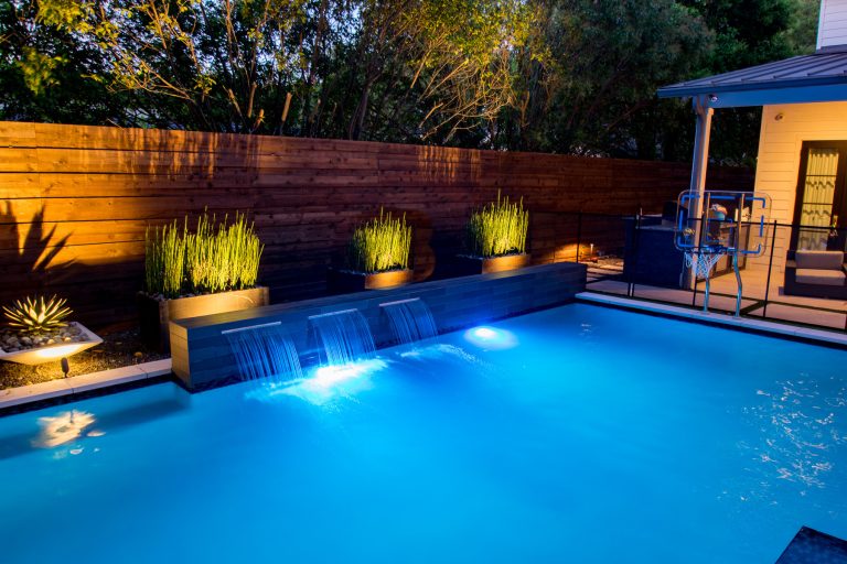 Dallas small yard - beautiful modern pool project with outdoor living and a putting green designed by Mike Farley. Pool is surrounded by a safety fence. FarleyPoolDesigns.com