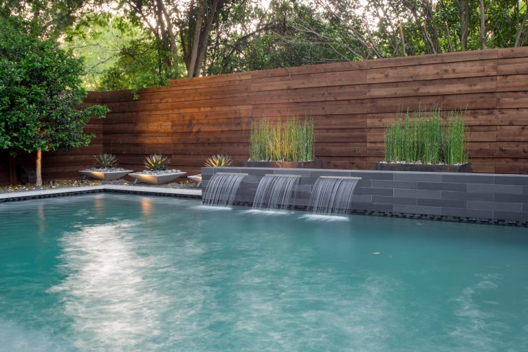 Dallas small yard - beautiful modern pool project with outdoor living and a putting green designed by Mike Farley. Pool is surrounded by a safety fence. FarleyPoolDesigns.com