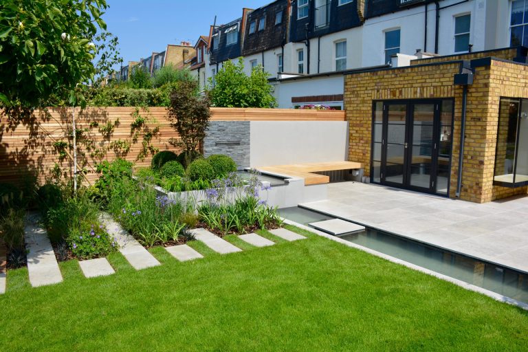 Design ideas for a mid-sized contemporary full sun backyard stone pond in London for summer.