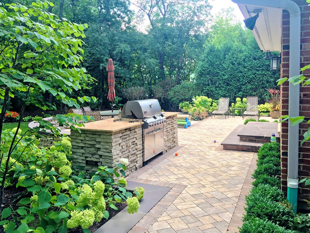 Designed and Built by: Arrow. Land + Structures. Professional Landscape Architects, Designers, and Builders. Elegant backyard concrete paver patio kitchen photo in Chicago with no cover by Arrow. Land + Structures | Outdoor Kitchens | Backyard Design | Outdoor Living Spaces | Landscape Design