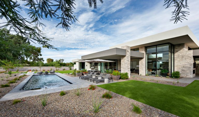 Modern Retreat is one of a four home collection located in Paradise Valley, Arizona. The site, formerly home to the abandoned Kachina Elementary School, offered remarkable views of Camelback Mountain. Nestled into an acre-sized, pie shaped cul-de-sac, the site’s unique challenges came in the form of lot geometry, western primary views, and limited southern exposure. While the lot’s shape had a heavy influence on the home organization, the western views and the need for western solar protection created the general massing hierarchy.

The undulating split-faced travertine stone walls both protect and give a vivid textural display and seamlessly pass from exterior to interior. The tone-on-tone exterior material palate was married with an effective amount of contrast internally. This created a very dynamic exchange between objects in space and the juxtaposition to the more simple and elegant architecture.

Maximizing the 5,652 sq ft, a seamless connection of interior and exterior spaces through pocketing glass doors extends public spaces to the outdoors and highlights the fantastic Camelback Mountain views.

Project Details // Modern Retreat
Architecture: Drewett Works
Builder/Developer: Bedbrock Developers, LLC
Interior Design: Ownby Design
Photographer: Thompson Photographic by Drewett Works | Pool design | Pool Contracting | Swimming Pool Ideas | Swimming Pool Design Ideas