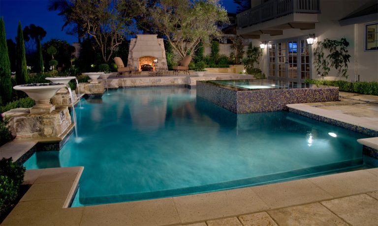 Elegant Classic pool with modern infinity edge spa, precast urn fountains and step up cozy fireplace retreat.