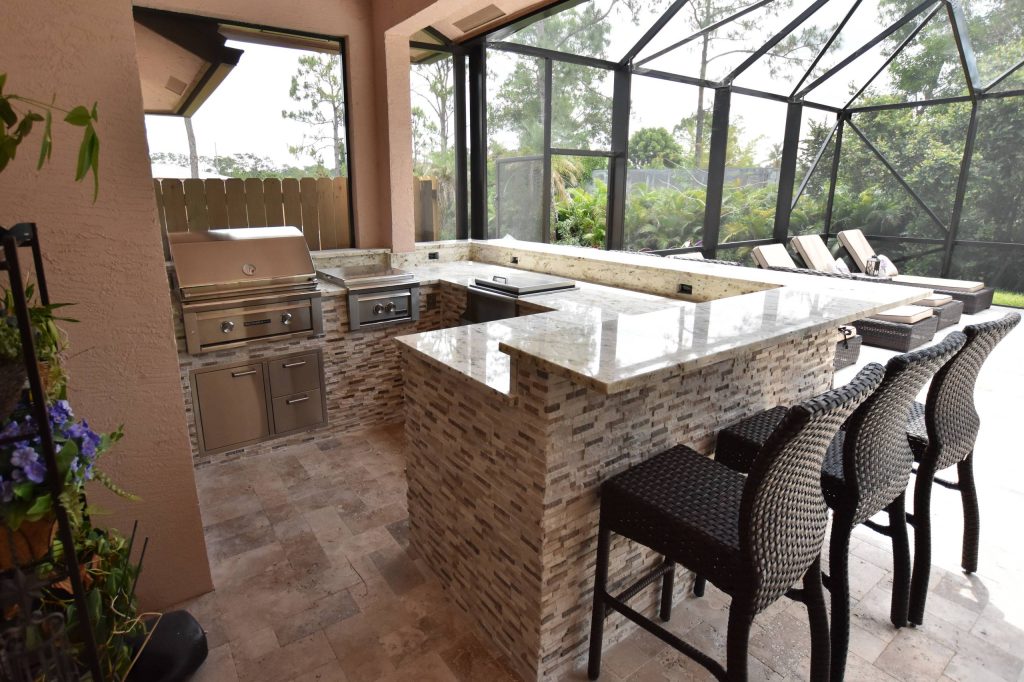 Elegant backyard brick patio kitchen photo in Miami with a roof extension