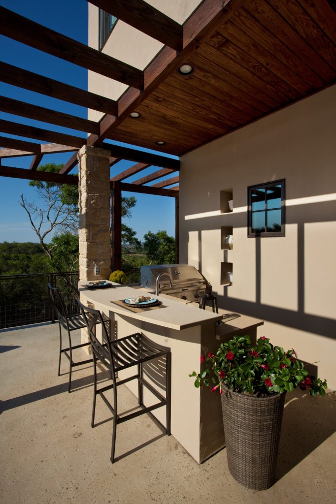 Elegant concrete patio kitchen photo in Austin with a roof extension