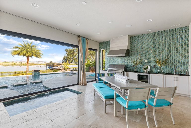 Everything you need for the perfect staycation - a roomy porch, outdoor kitchen, spa and pool, and a view of a beautiful lake.