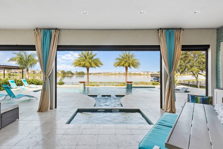 Everything you need for the perfect staycation - a roomy porch, outdoor kitchen, spa and pool, and a view of a beautiful lake.