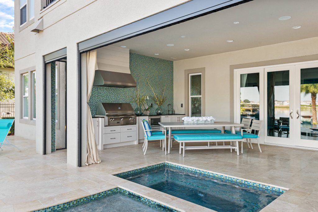 Everything you need for the perfect staycation - a roomy porch, outdoor kitchen, spa and pool, and a view of a beautiful lake.