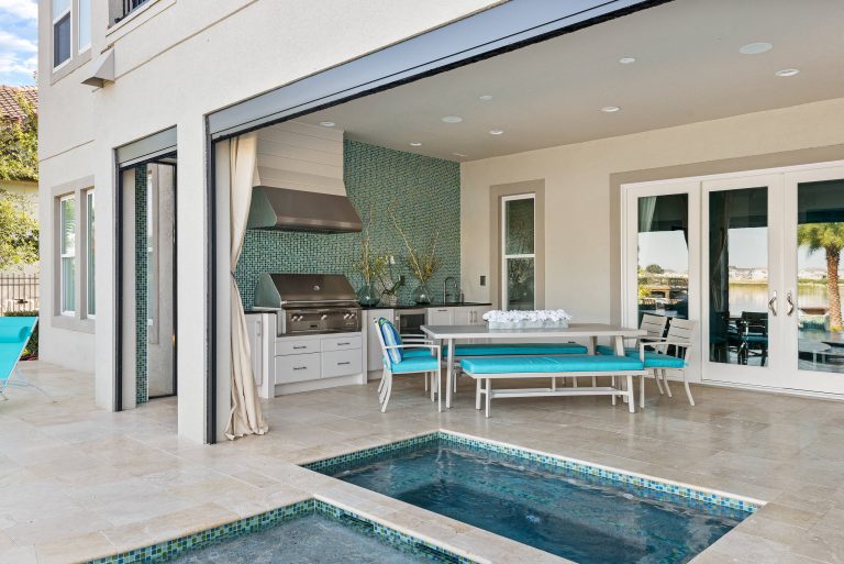 Everything you need for the perfect staycation - a roomy porch, outdoor kitchen, spa and pool, and a view of a beautiful lake.