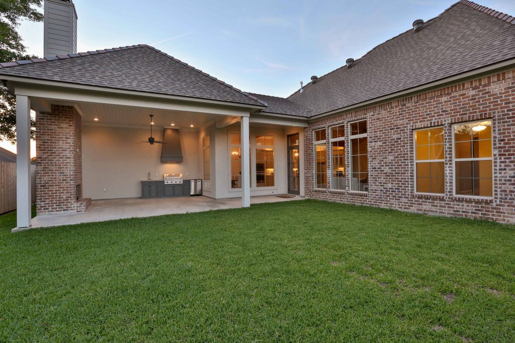 Example of a cottage backyard concrete patio kitchen design in New Orleans with a roof extension