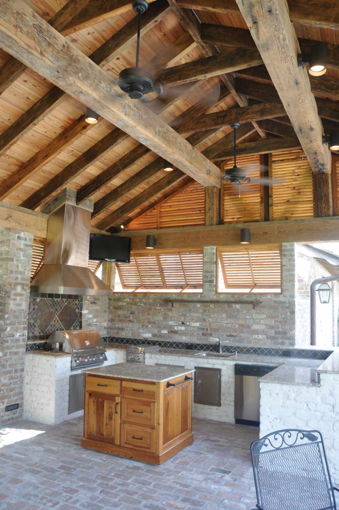 Example of a huge mountain style backyard brick patio kitchen design in New Orleans with a roof extension