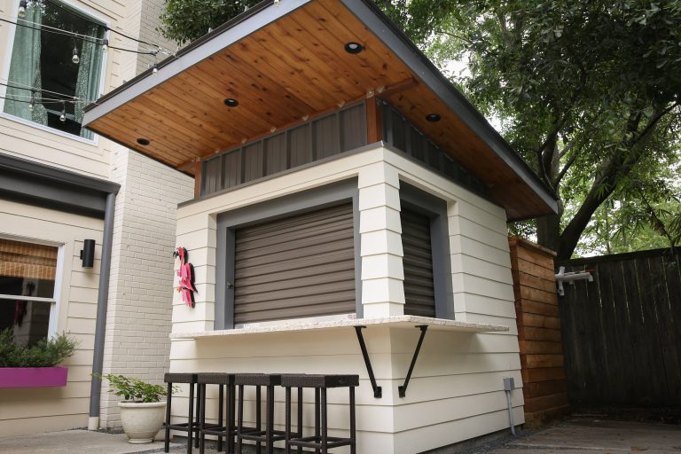 Example of a large arts and crafts backyard concrete patio kitchen design in Houston with a roof extension