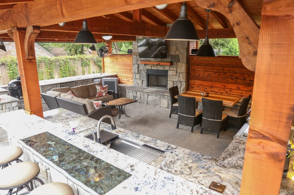 Example of a large arts and crafts backyard concrete patio kitchen design in Other with a pergola