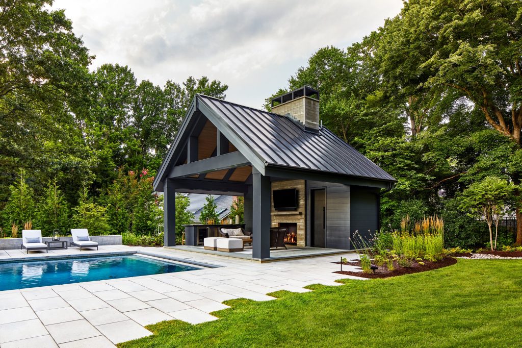 Example of a large backyard concrete paver and rectangular pool house design in DC Metro