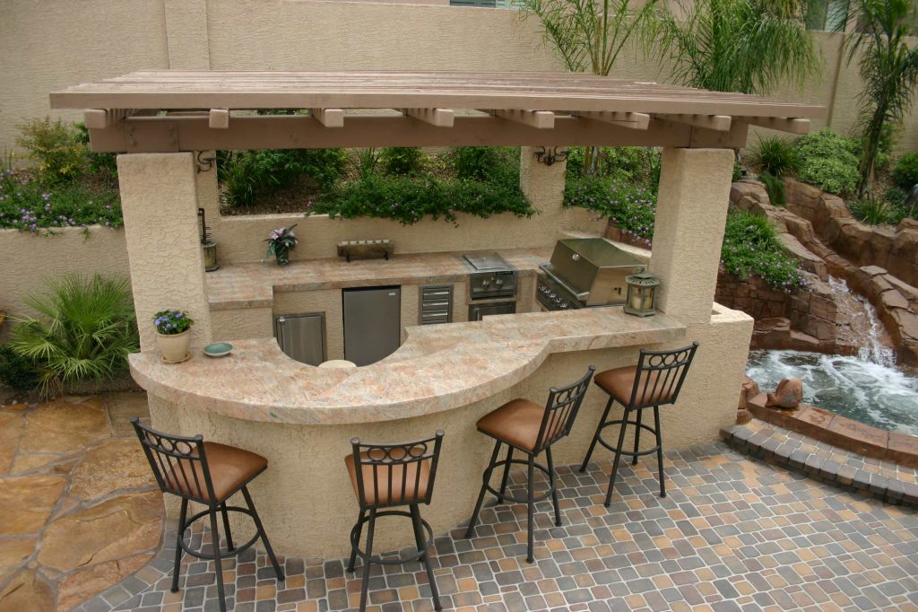 Example of a large backyard stone patio kitchen design in Las Vegas with no cover