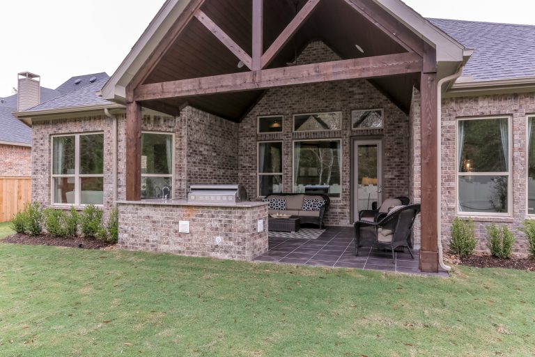 Example of a large backyard tile patio kitchen design in Houston with a roof extension