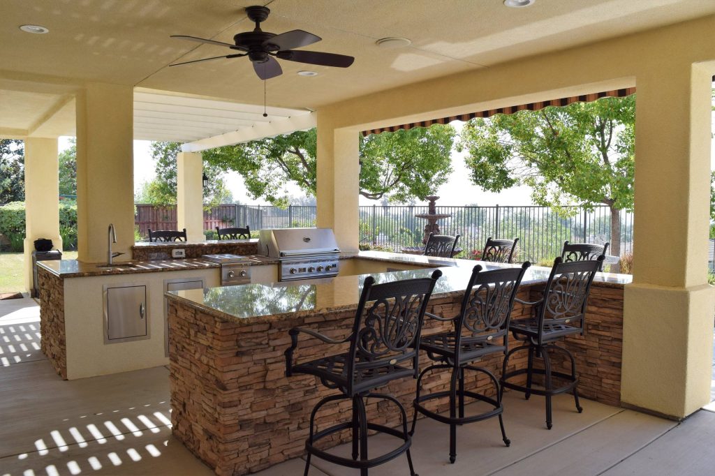 Example of a large classic backyard concrete paver patio kitchen design in Other with a roof extension