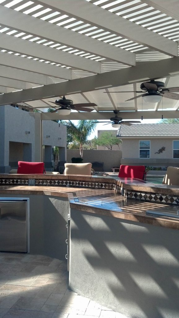 Example of a large classic backyard patio kitchen design in Phoenix with a pergola