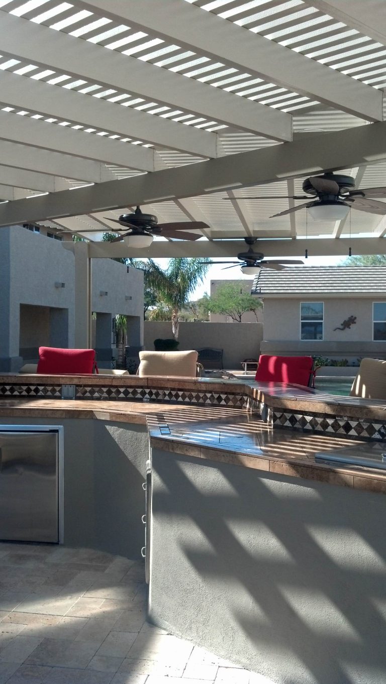 Example of a large classic backyard patio kitchen design in Phoenix with a pergola