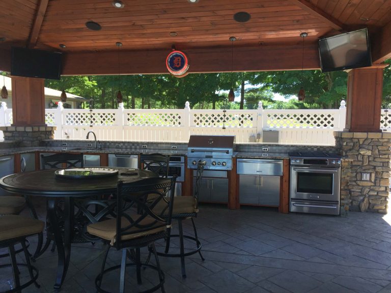 Example of a large classic backyard stamped concrete patio kitchen design in Grand Rapids with a pergola