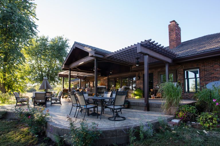 Example of a large classic backyard stamped concrete patio kitchen design in Kansas City with a pergola