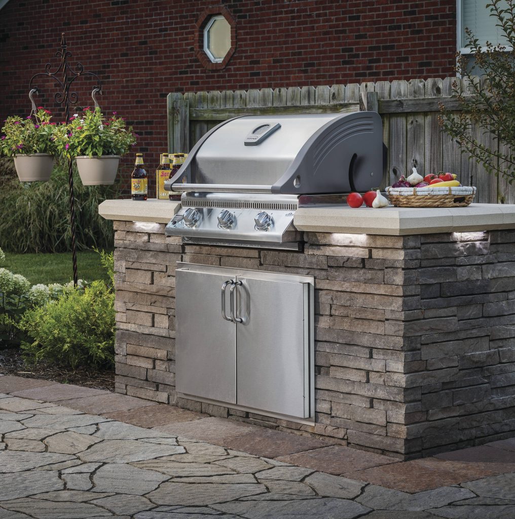 Example of a large classic backyard stone patio kitchen design in New York with no cover