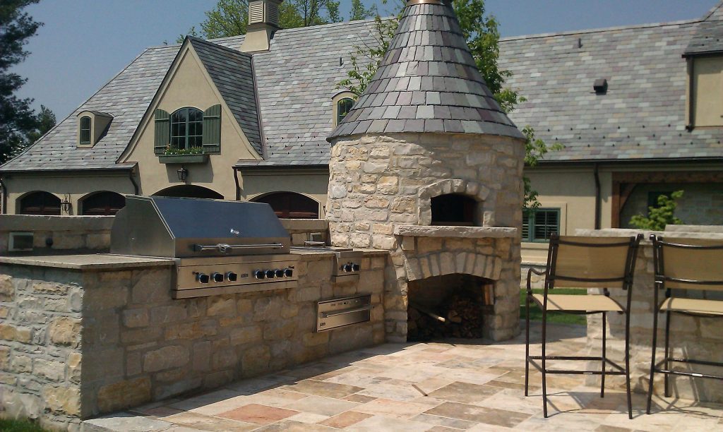 Example of a large classic backyard stone patio kitchen design in St Louis with no cover