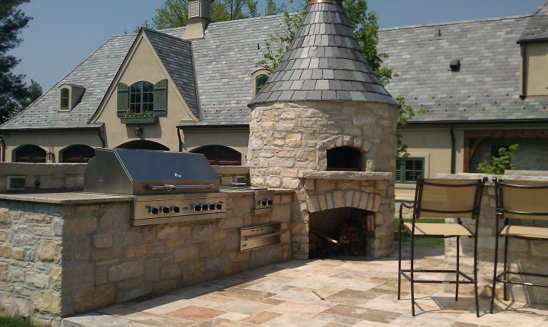 Example of a large classic backyard stone patio kitchen design in St Louis with no cover