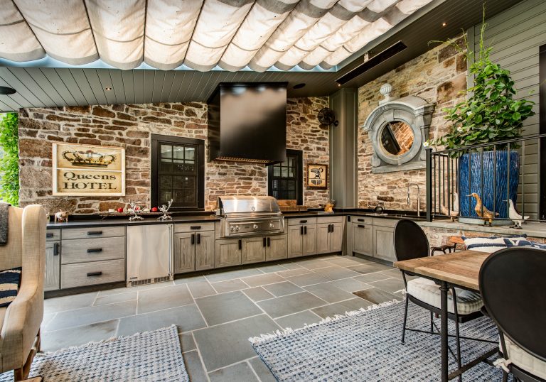 Example of a large cottage backyard concrete paver patio kitchen design in Philadelphia with an awning