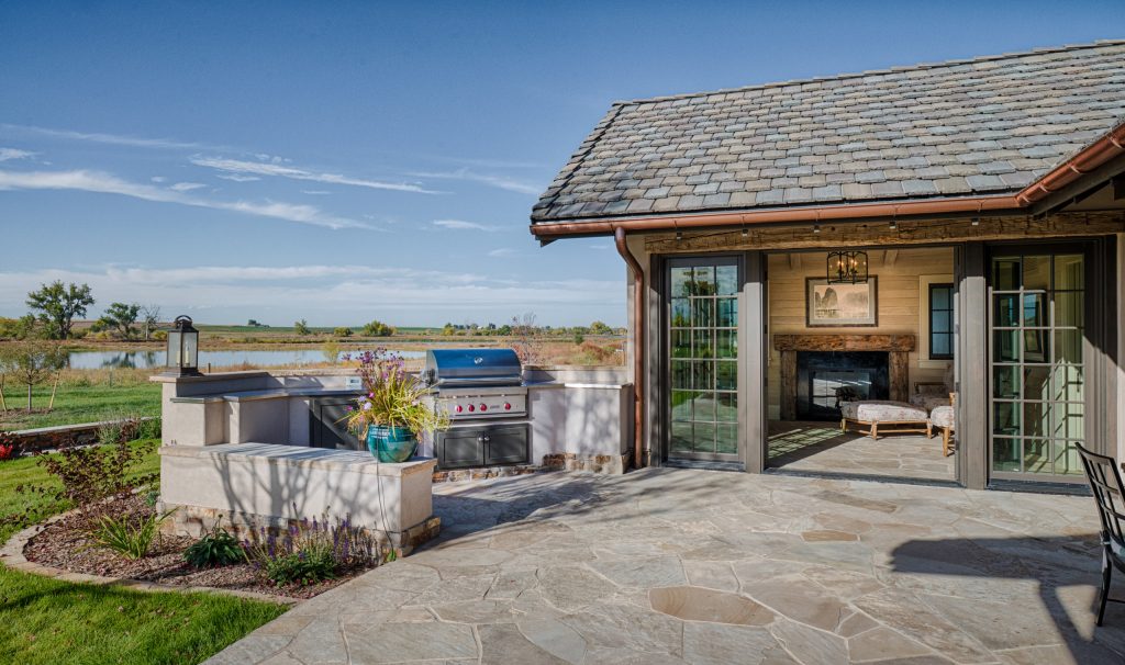 Example of a large cottage backyard patio kitchen design in Denver with a roof extension