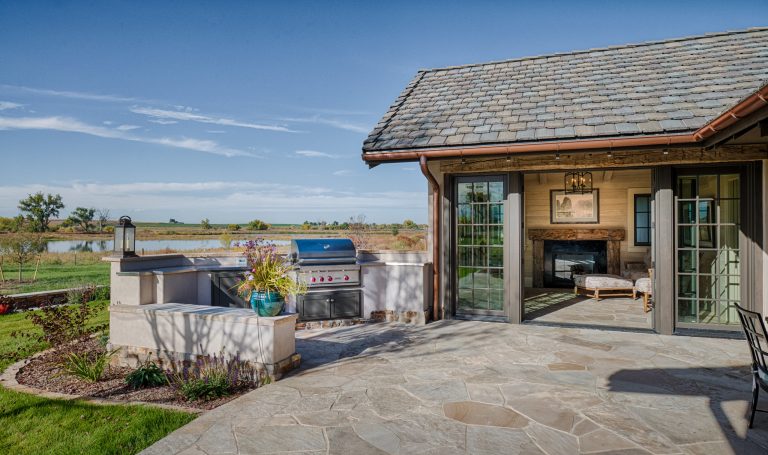 Example of a large cottage backyard patio kitchen design in Denver with a roof extension