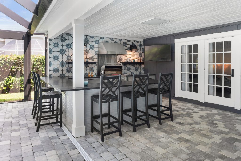 Example of a large eclectic backyard concrete paver patio kitchen design in Tampa with a roof extension