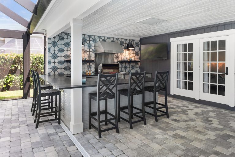 Example of a large eclectic backyard concrete paver patio kitchen design in Tampa with a roof extension