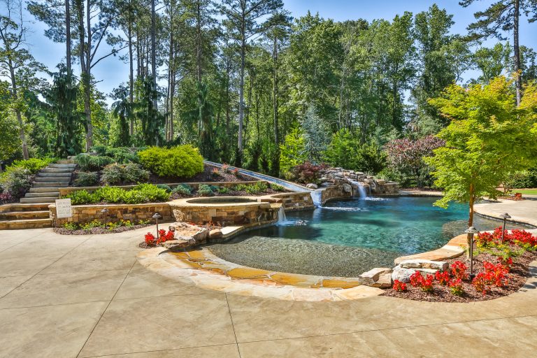 Example of a large island style backyard stamped concrete and custom-shaped natural water slide design in Atlanta
