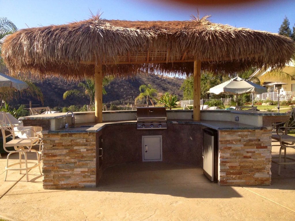 Example of a large island style backyard stamped concrete patio kitchen design in Orange County with a gazebo