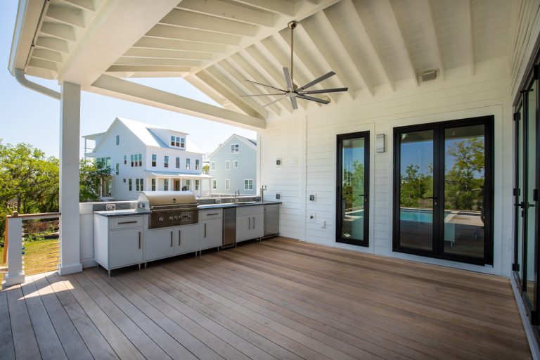 Example of a large minimalist backyard cable railing outdoor kitchen deck design in Charleston with a roof extension