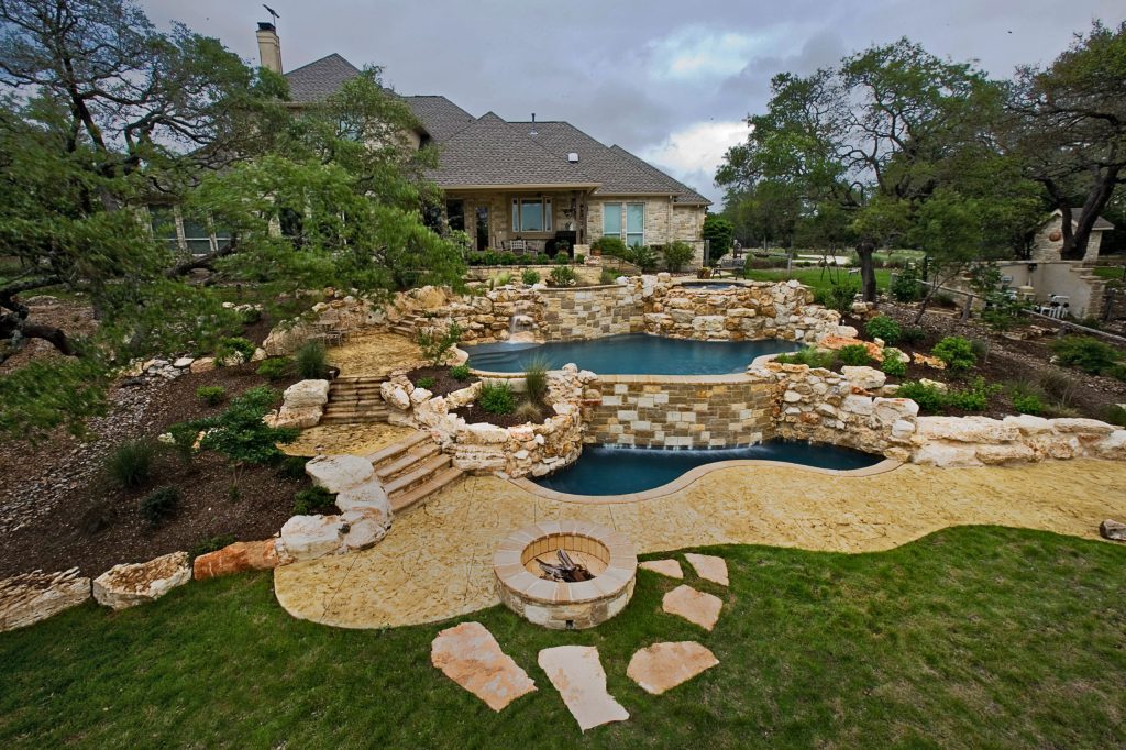 Example of a large mountain style backyard concrete and custom-shaped natural pool fountain design in Austin