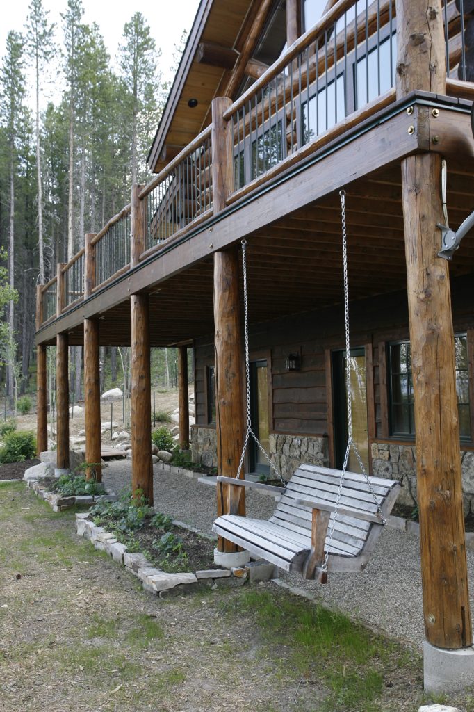 Example of a large mountain style backyard deck design in Denver with a roof extension