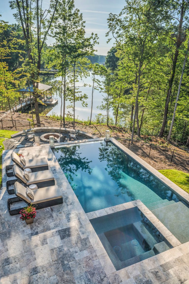 Example of a large mountain style backyard stone and rectangular infinity hot tub design in Charlotte