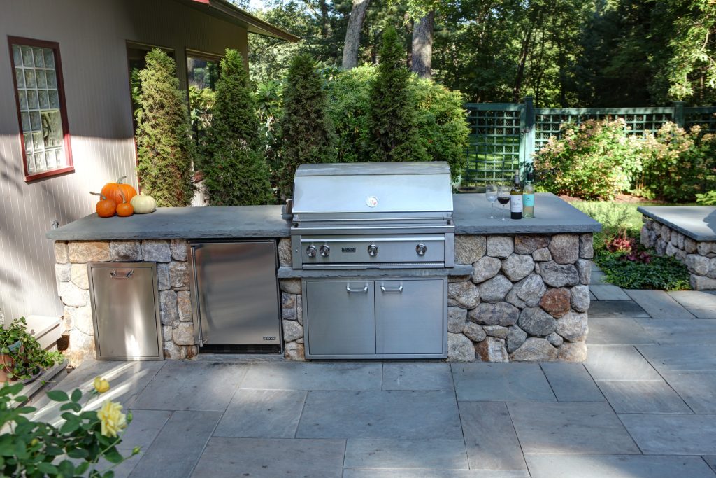 Example of a large mountain style backyard stone patio kitchen design in Boston with no cover
