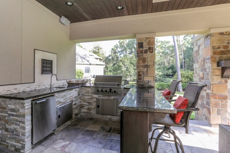 Example of a large mountain style backyard tile patio kitchen design in Houston with a roof extension