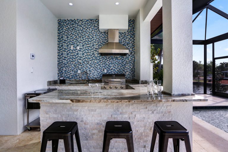 Example of a large transitional backyard stone patio kitchen design in Miami with a roof extension
