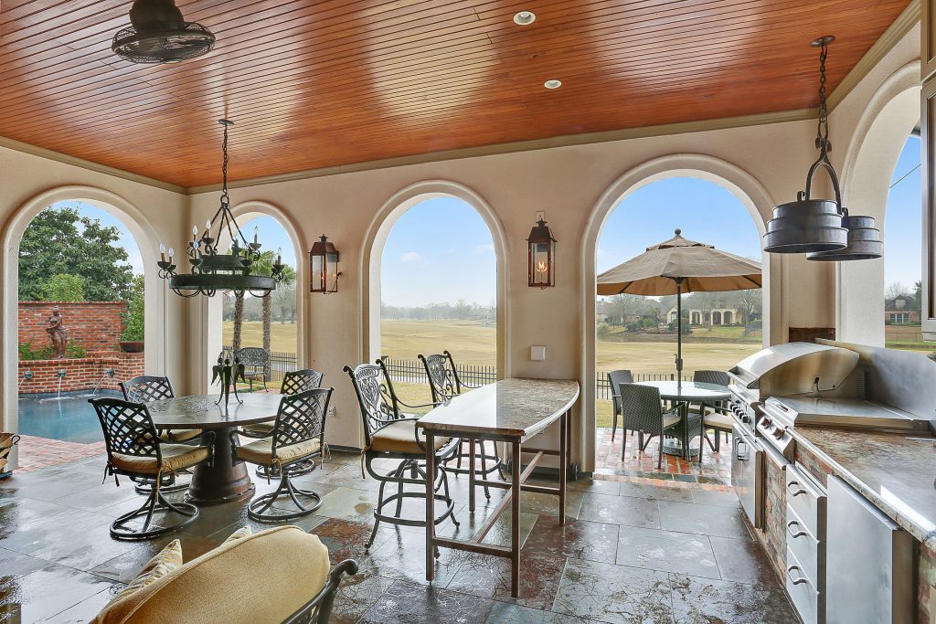 Example of a large transitional backyard stone patio kitchen design in New Orleans with a roof extension