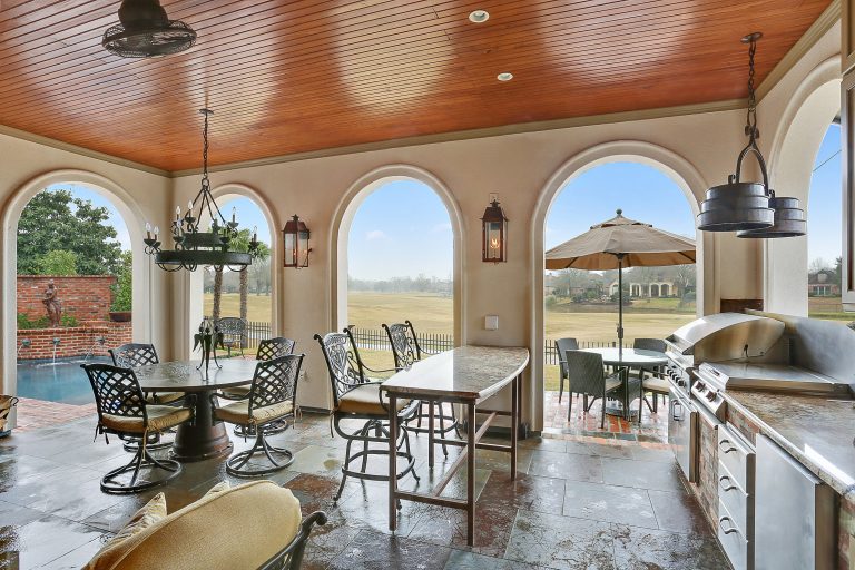 Example of a large transitional backyard stone patio kitchen design in New Orleans with a roof extension