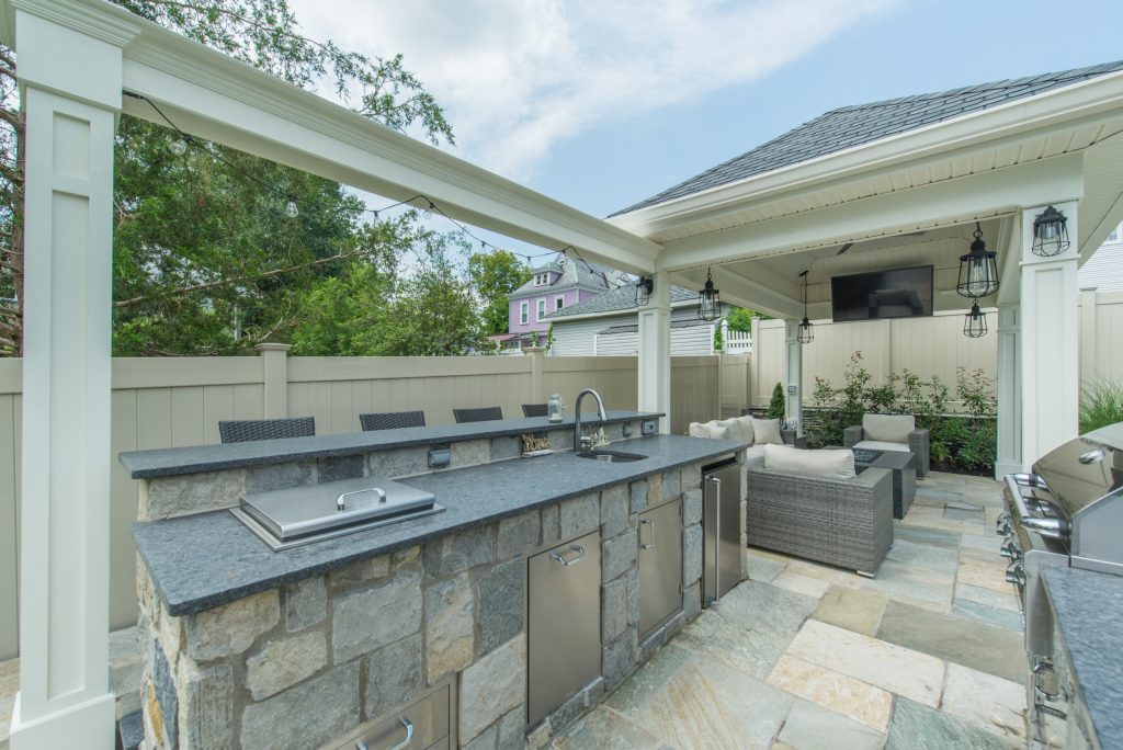 Example of a large transitional backyard stone patio kitchen design in New York with a gazebo