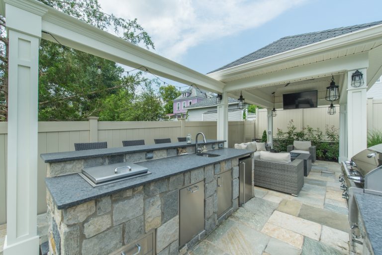 Example of a large transitional backyard stone patio kitchen design in New York with a gazebo