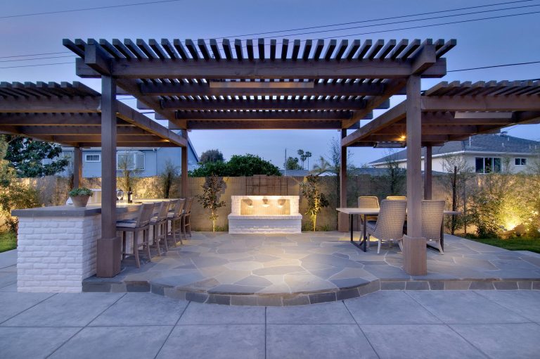 Example of a large transitional backyard stone patio kitchen design in Orange County with a pergola