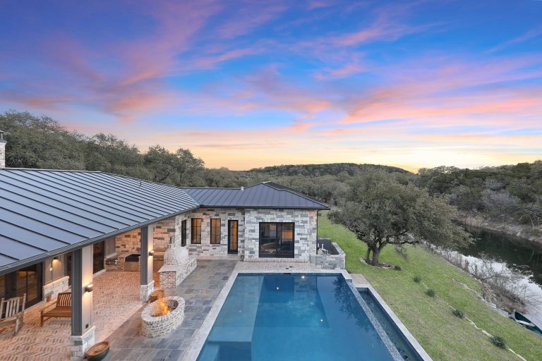 Example of a large trendy backyard brick and rectangular infinity pool fountain design in Austin